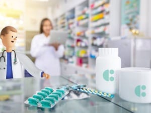 A picture showing a pharmacy technician on a System C Laptop with medicines on a countertop.