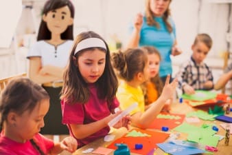 An image of children working hard in a classroom with a System C character watching over them.